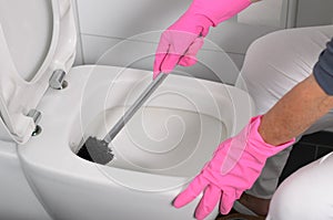 Woman in pink gloves cleaning the toilet