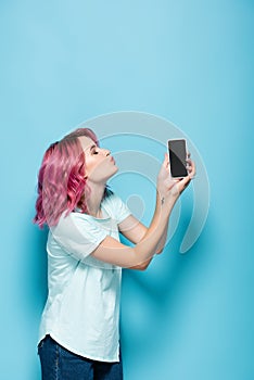 Woman with pink hair kissing smartphone