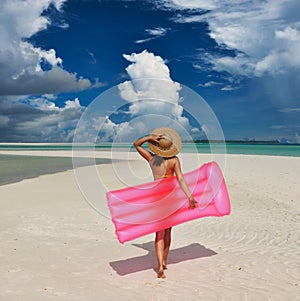 Woman with pink inflatable raft at the beach