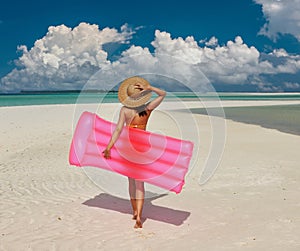 Woman with pink inflatable raft at the beach