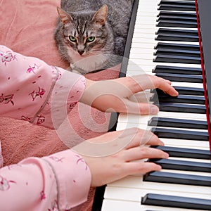 A woman in pink pajamas and a funny pet learn to play the piano on a home bed