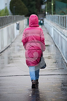 Woman with pink rain coat walking in the street