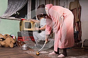 Woman in Pink Robe Cleaning a Messy Room