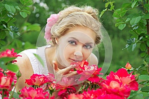 Woman in pink rose garden smelling