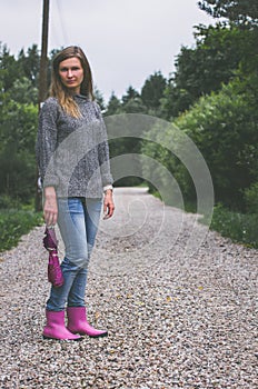 Woman in pink rubber boots with umbrella