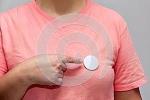 Woman in pink shirt pointing at a shiny round button. Isolated pin badge mockup