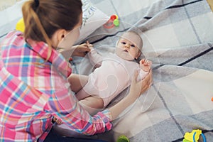 A woman in a pink shirt sits on the floor in living room and plays with her little child. Child really likes to play.