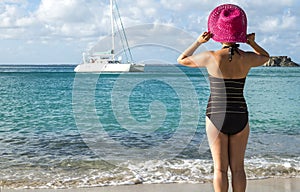 Woman with Pink Straw Hat Looking at a Catamaran