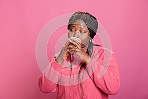 Woman with pink sweather holding cup of coffee drinking hot cappuccino having free time