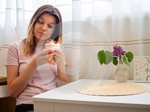 Woman in pink t-shirt sitting at a white table and trying to say no to junk food