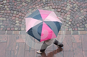 Woman with pink umbrella on cobbles place