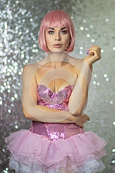 Woman in a pink wig with short hair on a silver shiny background