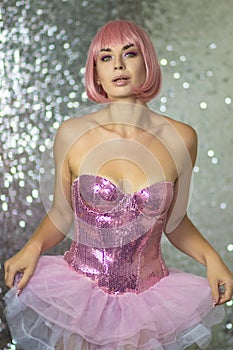 Woman in a pink wig with short hair on a silver shiny background