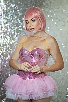 Woman in a pink wig with short hair on a silver shiny background