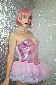 Woman in a pink wig with short hair on a silver shiny background