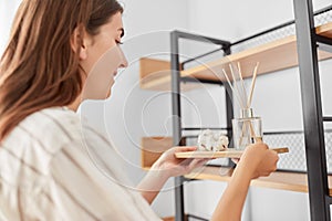 Woman placing aroma reed diffuser to shelf home