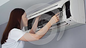 Woman placing back clean filter into air conditioner