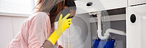 Woman Placing Bucket Under The Sink Pipe