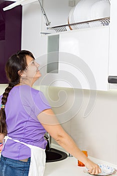 Woman placing clean dishes back on the rack