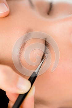 Woman placing fake eyelash on a patient