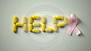 Woman placing pink ribbon near help word made of pills on table, breast cancer