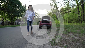 Woman is placing a warning triangle and calling roadside assistance.