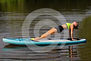 Woman planking backwards on SUP at water