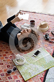 Woman planning summer vacation abroad, going on trip alone. Lying on carpet, daydreaming about adventures.