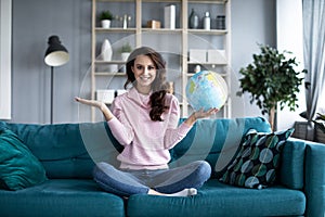 Woman planning a trip or summer vacation with globe of the world laughing and smiling. Travelling concept