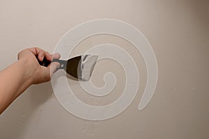 Woman plasterer repairing wall with putty. Close-up, copy space