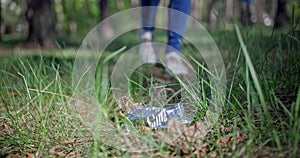 A woman with a plastic bag collects garbage in the forest by impaling it on a stick