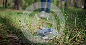 A woman with a plastic bag collects garbage in the forest by impaling it on a stick