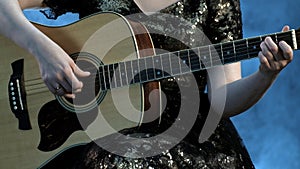 Woman play on the guitar. The fingers of the left hand of the beautiful girl clamp on the strings a chord in E minor.