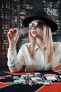 Woman player hold poker chips on the table with card in a casino