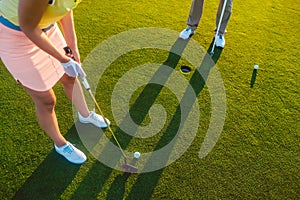 Woman player ready to hit the ball into the hole at the end of a game