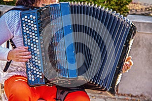 Woman playing accordian outdoors - Selective focus and some motion blur on hands - Colorful and cropped