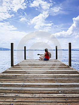 Woman playing acoustic guitar by the lake