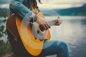 Woman playing acoustic guitar by lake, girl strumming guitar