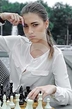 Woman playing with black pieces in chess.