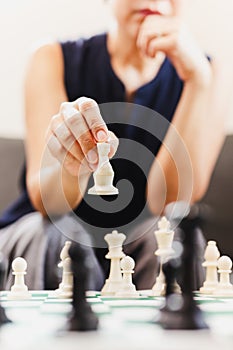 Woman playing chess board game at home.