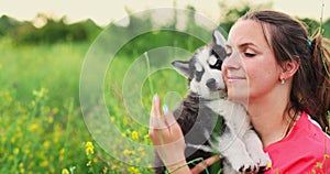 Woman playing with cute little husky puppy dog outdoors. Pet and owner love.