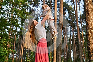 Woman playing with daughter raising her up in her arms outdoor