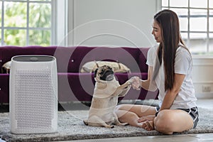 Woman playing with Dog Pug Breed and Air purifier in cozy white living room