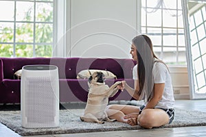 Woman playing with Dog Pug Breed and Air purifier in cozy white living room