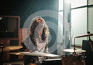 Woman playing drums during music band rehearsal