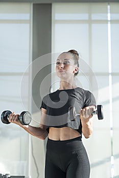 Woman are playing dumbbells to build muscle. Muscular young female exercising with dumbbells