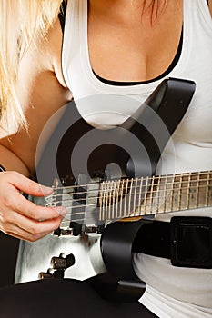 Woman playing on electric guitar, black background