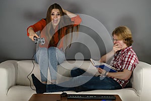 Woman playing games man reading book