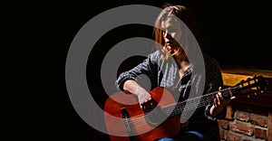 Woman playing guitar, holding an acoustic guitar in his hands. Music concept. Girl guitarist plays