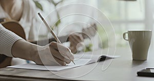 Woman playing guitar at home and composing music